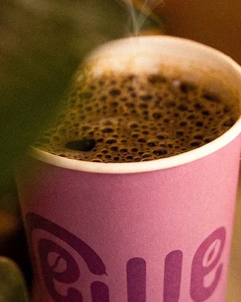 A freshly brewed black coffee in a pink Brewed cup, steam rising